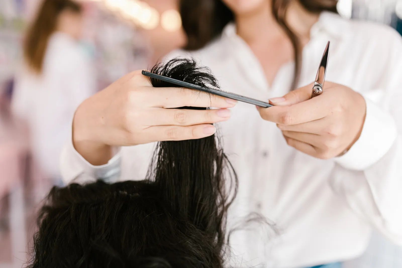 A stylist sectioning hair with a comb, mid-cut